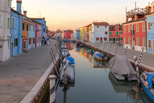 The typical colored houses reflected in a canal in Burano Island at sunset, Venice, Veneto, Italy.