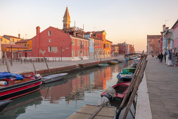 The typical colored houses and the leaning bell tower reflected in a canal in Burano Island, Venice, Veneto, Italy.