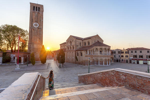 A woman admires the Church of Santa Maria e San Donato (Murano Cathedral) at sunset, Murano Island, Venice, Veneto, Italy.