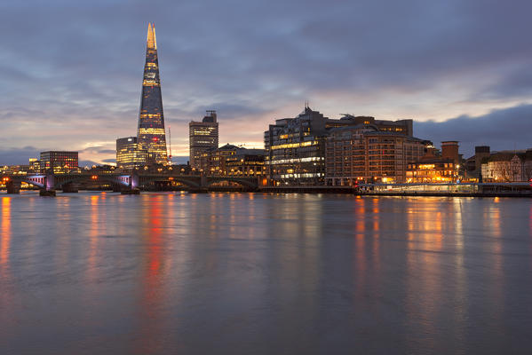 Southwark area with Shard and Southwark bridge reflected in river Thames during a cloudy dawn, London, Great Britain, UK