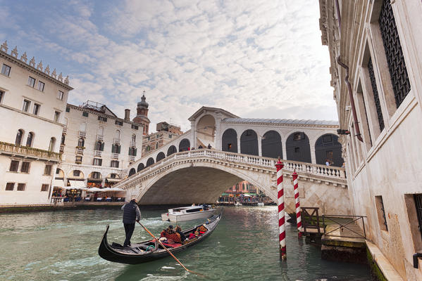 A traditional venetian gondola on Grand Canal, under Rialto Bridge, Venice, Veneto, Italy