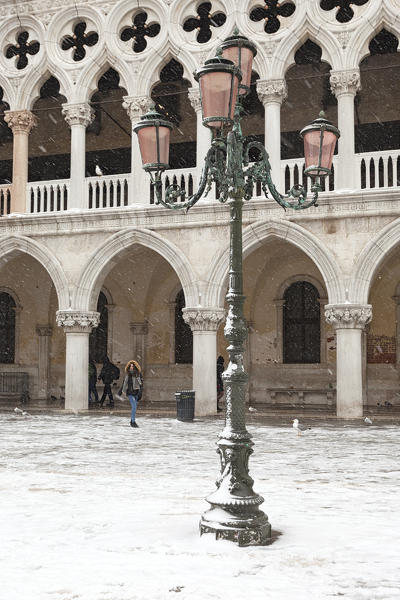 A tourist in St. Mark Square, in front of Doge’s Palace, during a snowfall, Venice, Veneto, Italy