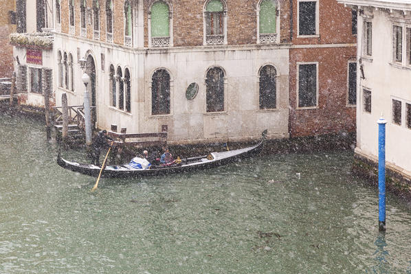 A traditional venetian gondola in Grand Canal during a snowfall, Venice, Veneto, Italy