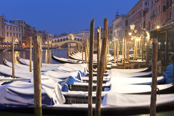 Rialto Bridge with snow-covered gondolas at dusk after a snowfall, Grand Canal, Venice, Veneto, Italy