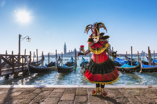Typical mask of Carnival of Venice in Riva degli Schiavoni with St. George's island in the background, Venice, Veneto, Italy