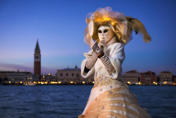 Typical mask of Carnival of Venice with Doge's Palace and bell tower of St. Mark in the background, Venice, Veneto, Italy