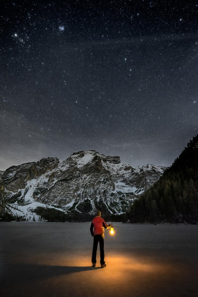 Braies/Prags, Dolomites, South Tyrol, Italy. 
Man with a lantern admires the mount Seekofel at the frozen Lake Braies
