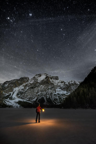 Braies/Prags, Dolomites, South Tyrol, Italy. 
Man with a lantern admires the mount Seekofel at the frozen Lake Braies