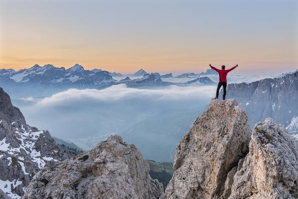 Gran Cir, Gardena Pass, Dolomites, Bolzano district, South Tyrol, Italy. A mountaineer admires the sunrise at the summit of the Gran Cir (MR)