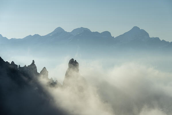 Gardena Pass, Dolomites, Bolzano district, South Tyrol, Italy, Europe. Fog drifts around some crags, in the background the three summits of the Tofane