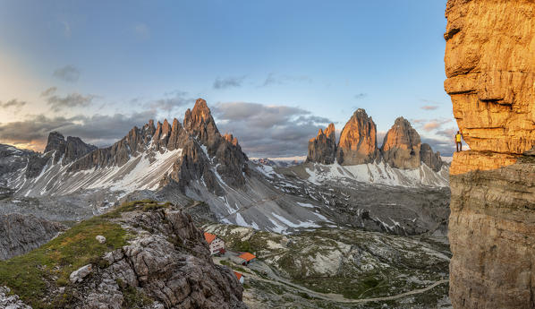 Sesto / Sexten, province of Bolzano, Dolomites, South Tyrol, Italy. A mountaineer admires the panorama from an exposed ledge at sunrise (MR)