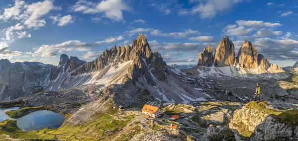 Sesto / Sexten, province of Bolzano, Dolomites, South Tyrol, Italy. A mountaineer admires the panorama at sunrise at the Tre Cime di Lavaredo, lakes Piani, Mount Paterno and refuge Locatelli (MR)
