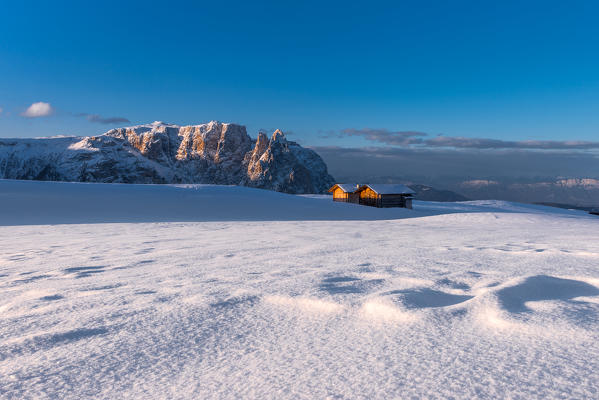 Alpe di Siusi/Seiser Alm, Dolomites, South Tyrol, Italy. Barns on plateau Bullaccia/Puflatsch. In the background the peaks of Sciliar/Schlern