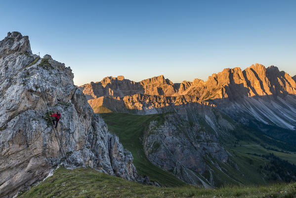 Funes Valley, Dolomites, South Tyrol, Italy. Climber on the Via Ferrata Günther Messner. In the background the Odle at Sunrise