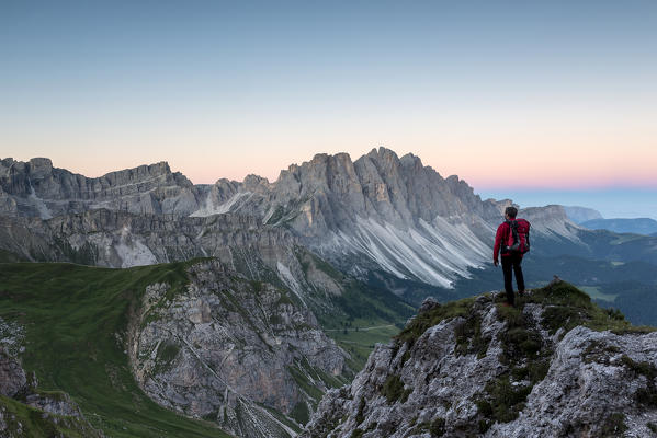 Funes Valley, Dolomites, South Tyrol, Italy. A hiker is waiting for the sunrise before the Odle