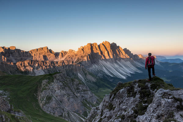Odle di Eores, Dolomites, South Tyrol, Italy. Hiker admires the sunrise on the Odle