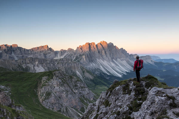 Odle di Eores, Dolomites, South Tyrol, Italy. Hiker admires the sunrise on the Odle