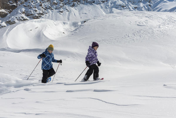 Fanes, Dolomites, South Tyrol, Italy. Children wearing snowshoes walking in the mountains of the Fanes