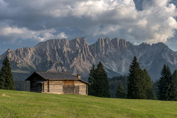 Carezza, Dolomites, South Tyrol, Italy. Mountain Hut in the pastures of Colbleggio. In the background the peaks of the Latemar