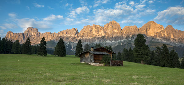 Carezza, Dolomites, South Tyrol, Italy. Mountain Hut in the pastures of Colbleggio. In the background the peaks of the Catinaccio group / Rosengarten