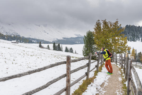 Funes Valley, Dolomites, South Tyrol, Italy. Hiker admires the Peaks of the Odle