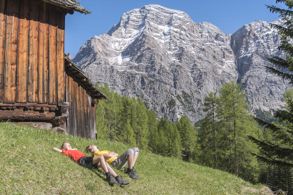 La Valle / Wengen, Alta Badia, Bolzano province, South Tyrol, Italy. Children relax on the pastures of Pra de Rit