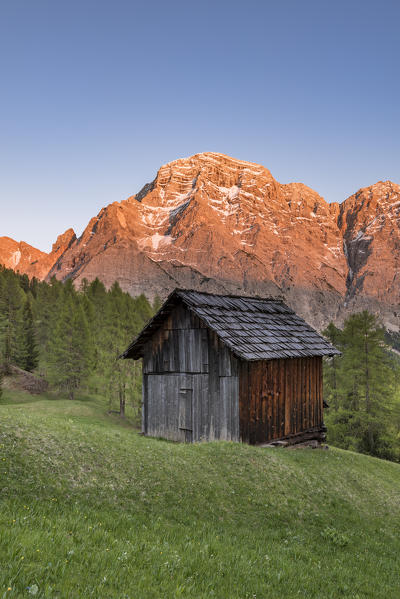 La Valle / Wengen, Alta Badia, Bolzano province, South Tyrol, Italy. Sunset on the pastures of Pra de Rit with the peak Cima Nove / Neunerspitze