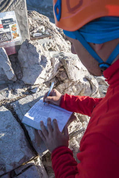 Sesto / Sexten, province of Bolzano, Dolomites, South Tyrol, Italy. Mountaineer sign the summitbook of Mount Paterno