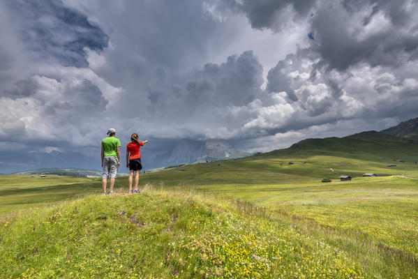 Alpe di Siusi/Seiser Alm, Dolomites, South Tyrol, Italy. Children look at storm clouds over the Sassolungo