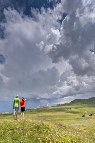 Alpe di Siusi/Seiser Alm, Dolomites, South Tyrol, Italy. Children look at storm clouds over the Sassolungo