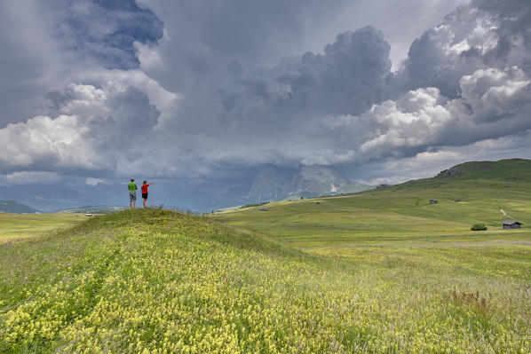 Alpe di Siusi/Seiser Alm, Dolomites, South Tyrol, Italy. Children look at storm clouds over Sassolungo