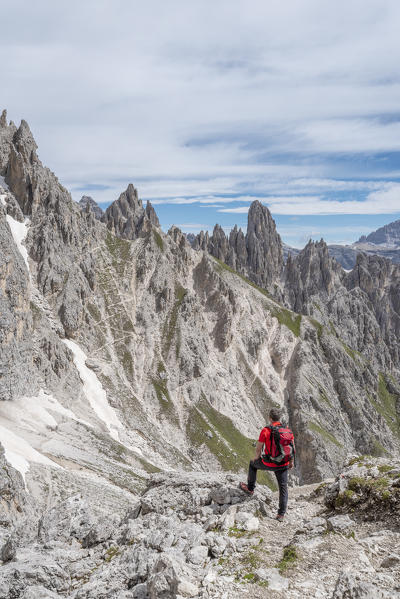Misurina, Cadini mountains, Dolomites, province of Belluno, Veneto, Italy. A mountaineer admires the mountain panorama in the saddle Ciadin Deserto