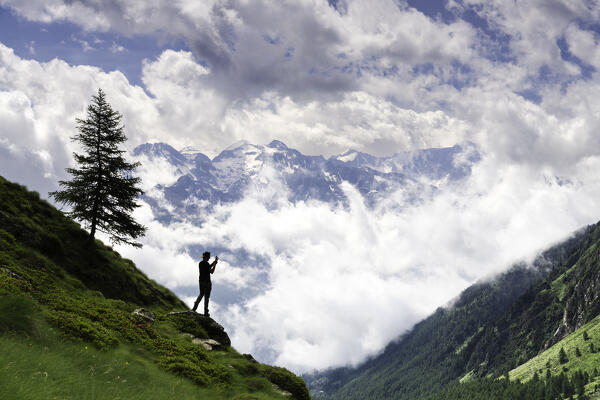 Hiker photographing the panorama of Val Canè in Valle Camonica, Brescia province in Italy, Lombardy, Italy.