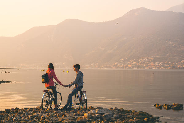 Pair of cyclists at sunset, iseo lake, Brescia province, Lombardy district, Italy.