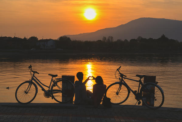 Pair of cyclists at sunset, iseo lake, Brescia province, Lombardy district, Italy.