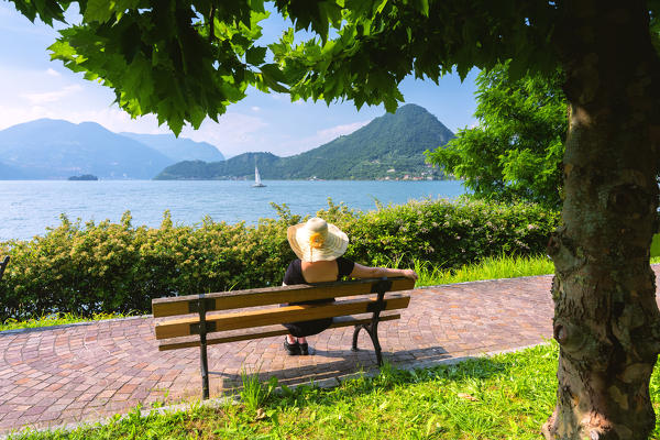 Woman on the bench in Iseo lake, Lombardy district, Brescia province, Italy.