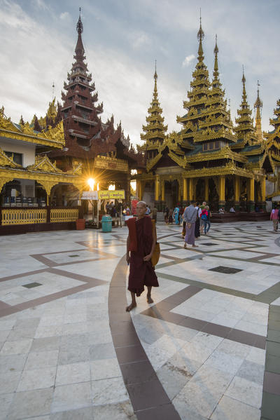 Yangon, Myanmar (Burma). Old monk walking in the Shwedagon pagoda at sunrise.