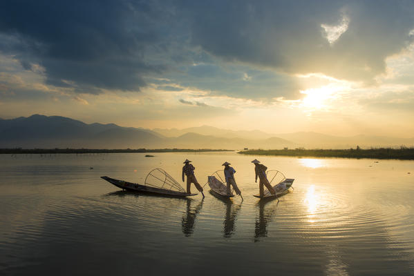 Inle lake, Nyaungshwe township, Taunggyi district, Myanmar (Burma). Three local fishermen in silhouette at sunrise.