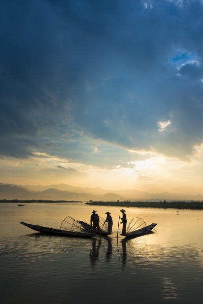 Inle lake, Nyaungshwe township, Taunggyi district, Myanmar (Burma). Three local fishermen in silhouette at sunrise.