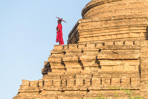 Bagan, Mandalay region, Myanmar (Burma). A young monk on top of a stupa.
