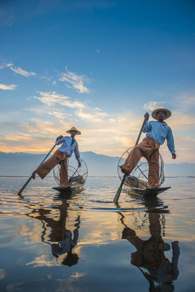 Inle lake, Nyaungshwe township, Taunggyi district, Myanmar (Burma). Local fishermen rowing with their typical conic fishing net.