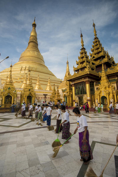 Yangon, Myanmar (Burma). Women sweeping the marble floor of the Shwedagon pagoda.