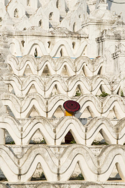 Mingun, Sagaing region, Myanmar (Burma). Woman with red umbrella in the middle of the white terraces of the Hsinbyume white pagoda.