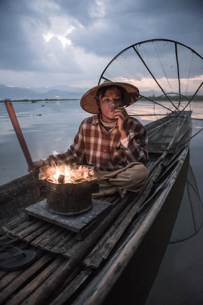 Inle lake, Nyaungshwe township, Taunggyi district, Myanmar (Burma). Local fisherman before dawn with fireplace on the boat.