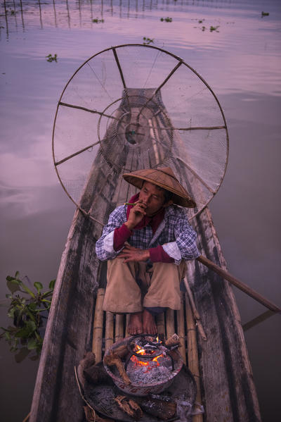 Inle lake, Nyaungshwe township, Taunggyi district, Myanmar (Burma). Local fisherman before dawn with fireplace on the boat.