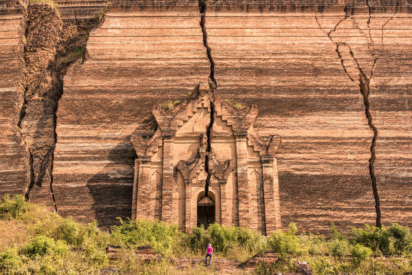 Mingun, Sagaing region, Myanmar (Burma). Woman with red umbrella looks at the Pahtodawgyi incomplete pagoda.