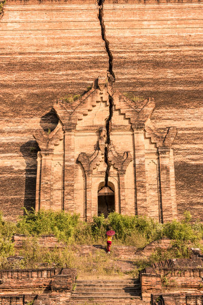 Mingun, Sagaing region, Myanmar (Burma). Woman with red umbrella looks at the Pahtodawgyi incomplete pagoda.