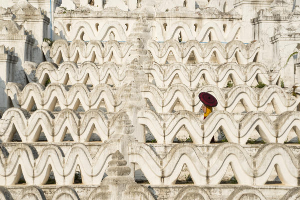 Mingun, Sagaing region, Myanmar (Burma). Woman with red umbrella in the middle of the white terraces of the Hsinbyume white pagoda.