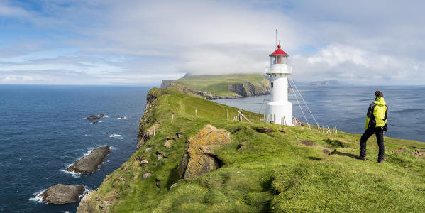 Mykines island, Faroe Islands, Denmark. Man watching the lighthouse from the top of the cliff. (MR)