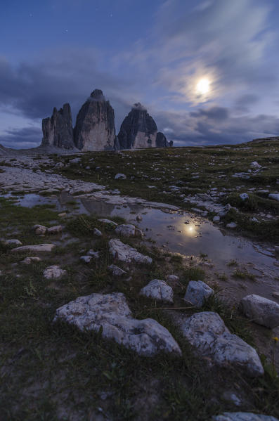 tre Cime di Lavaredo, Three peaks of lavaredo, Drei Zinnen, Dolomites, South Tyrol, Veneto, Italy. Moon and Tre Cime di Lavaredo are reflected in water